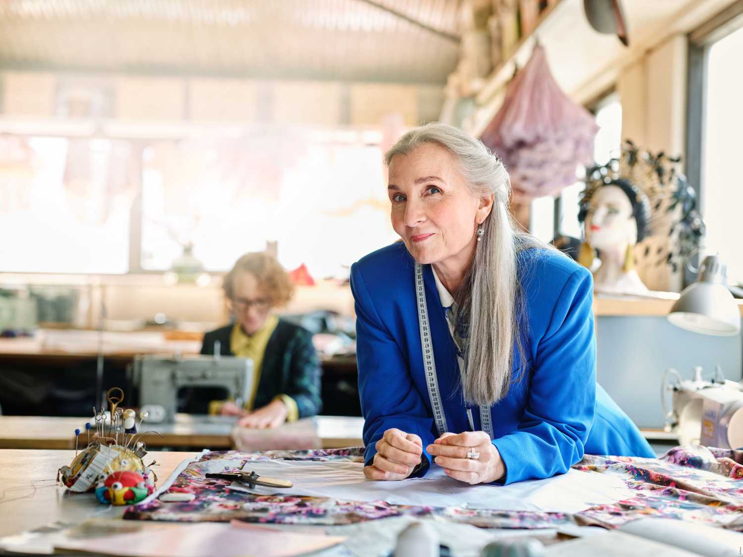 Mode Designerin an einem Arbeitstisch voller Nähutensilien